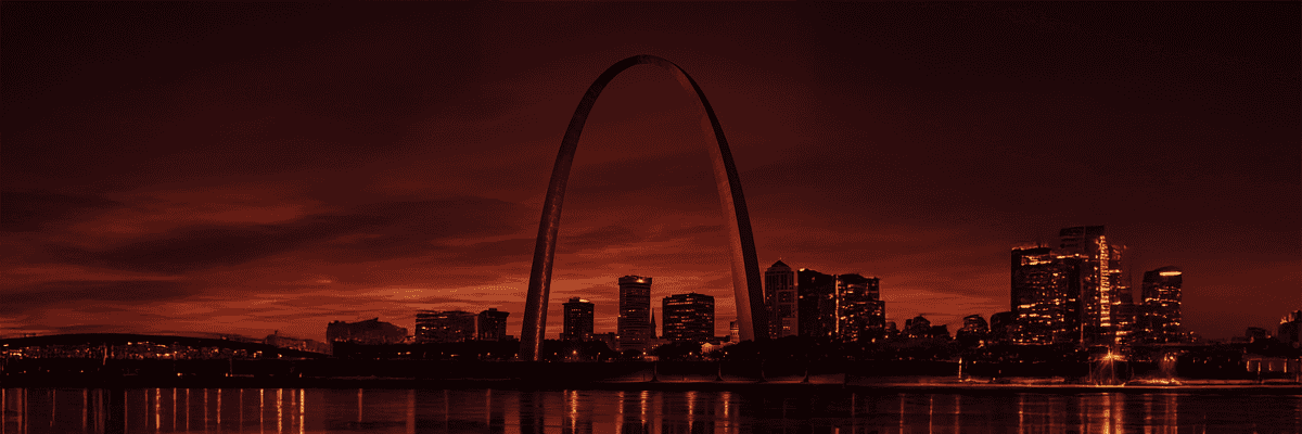 Beautiful view of downtown St. Louis at sunset with the iconic Gateway Arch illuminated, reflecting off the Mississippi River, highlighting real estate and property opportunities in the area.